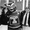 Hooter hugs two alumni.