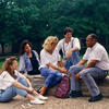 A group of alumni relax outdoors on campus.